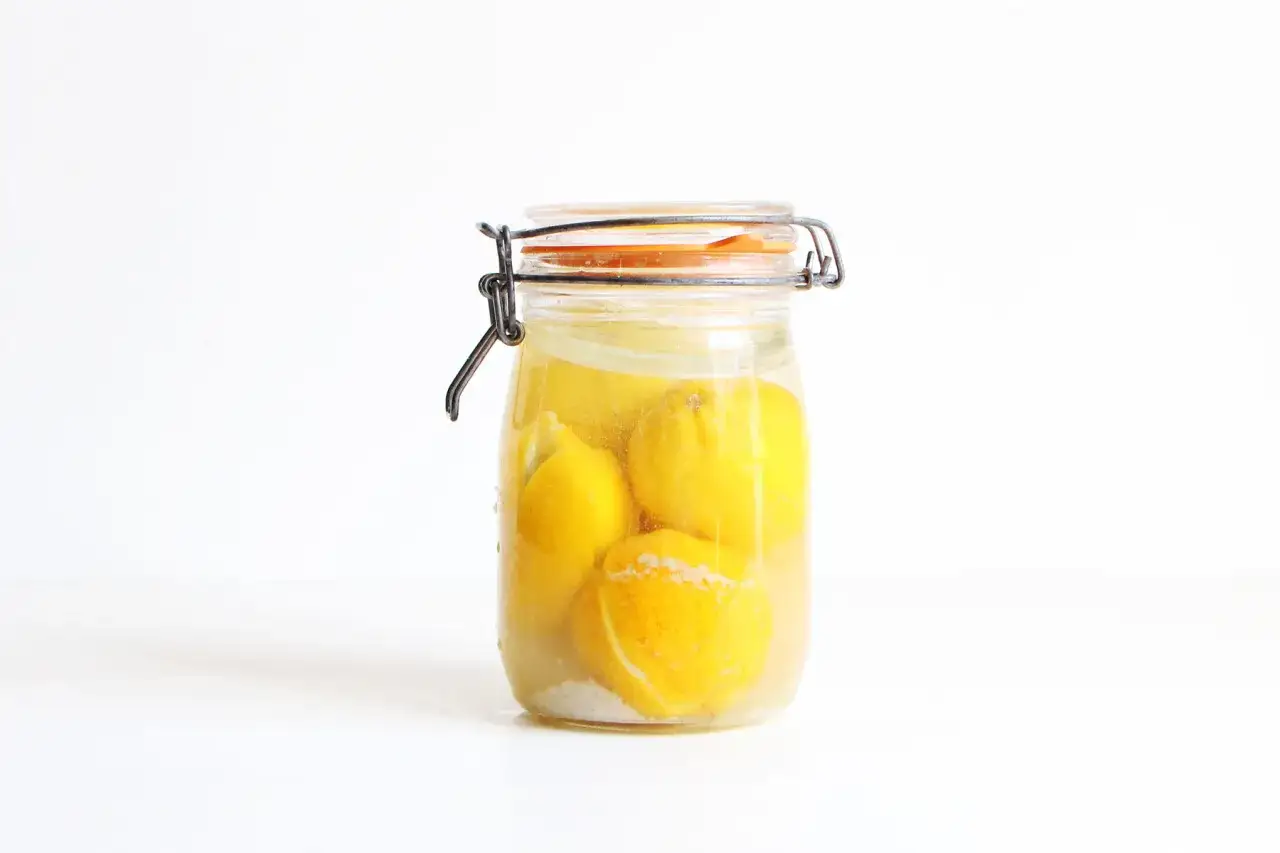 Bocal en verre rempli de citrons entiers et de gros sel, pr&ecirc;ts &agrave; confire.