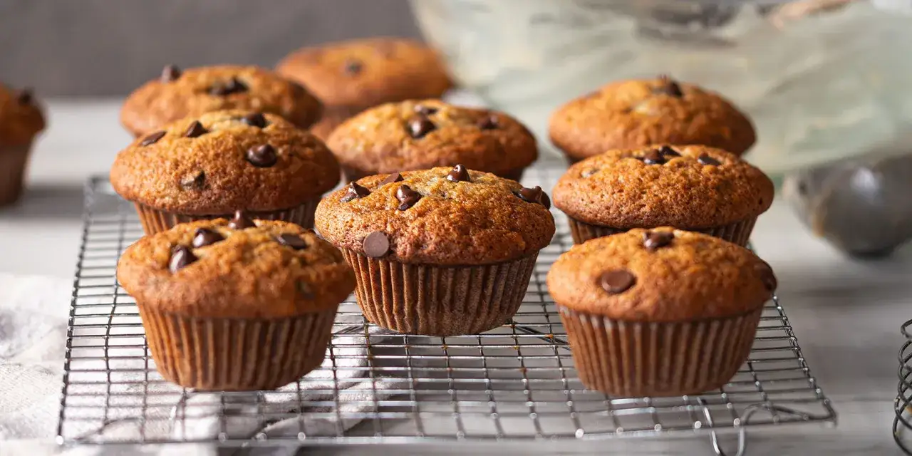 Muffins banane chocolat dorés et moelleux, parsemés de pépites de chocolat, refroidissant sur une grille.