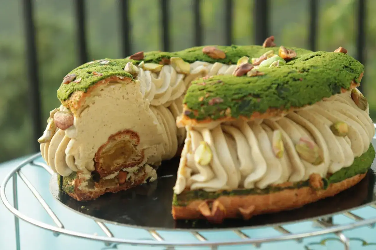 Un Paris-Brest pistache généreusement garni de crème onctueuse et parsemé de pistaches croquantes. Un délice visuel et gustatif.