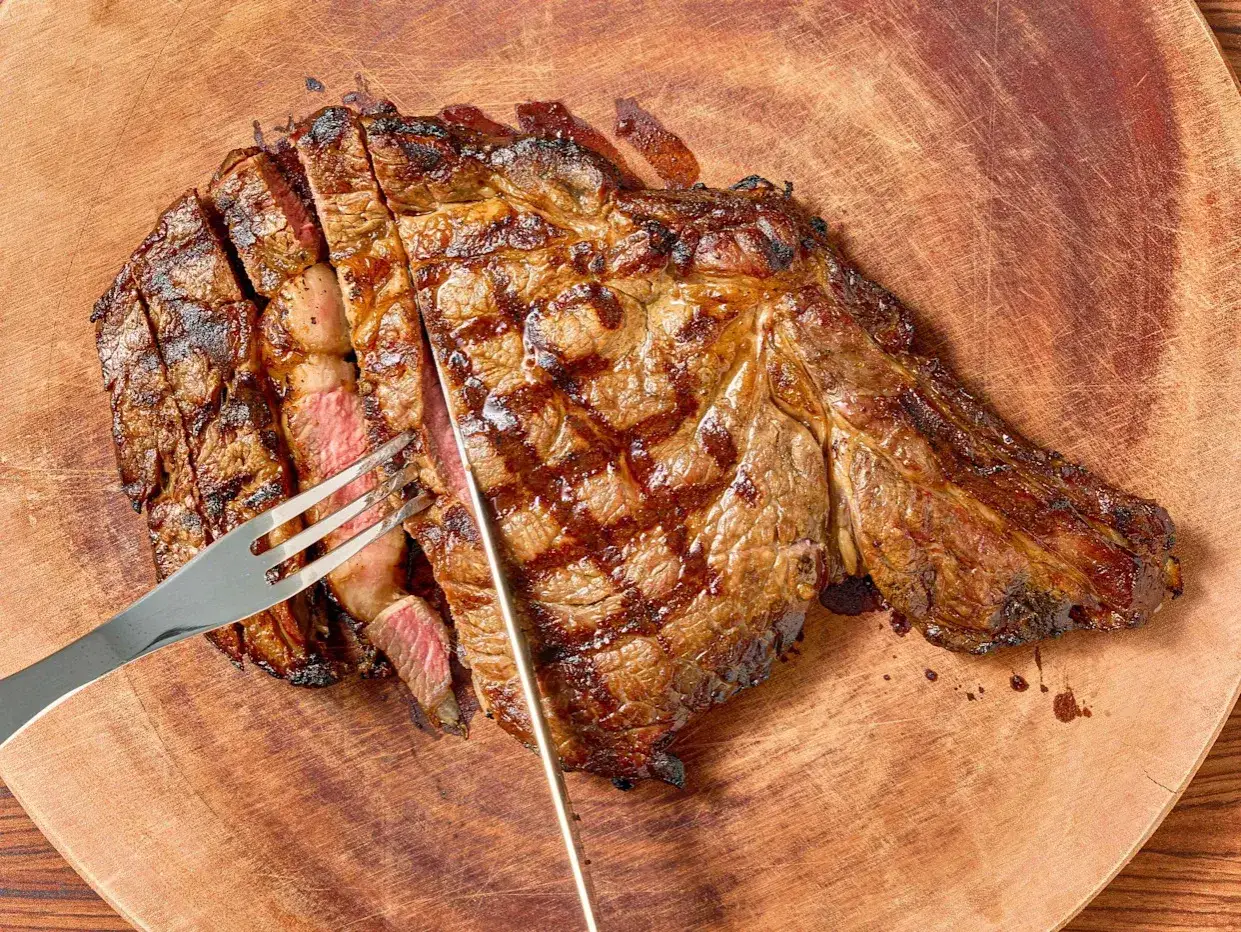 Un steak grillé, coupé en tranches, est prêt à être dégusté. La fourchette et le couteau suggèrent qu'il est temps d'attendrir la viande pour un repas parfait.