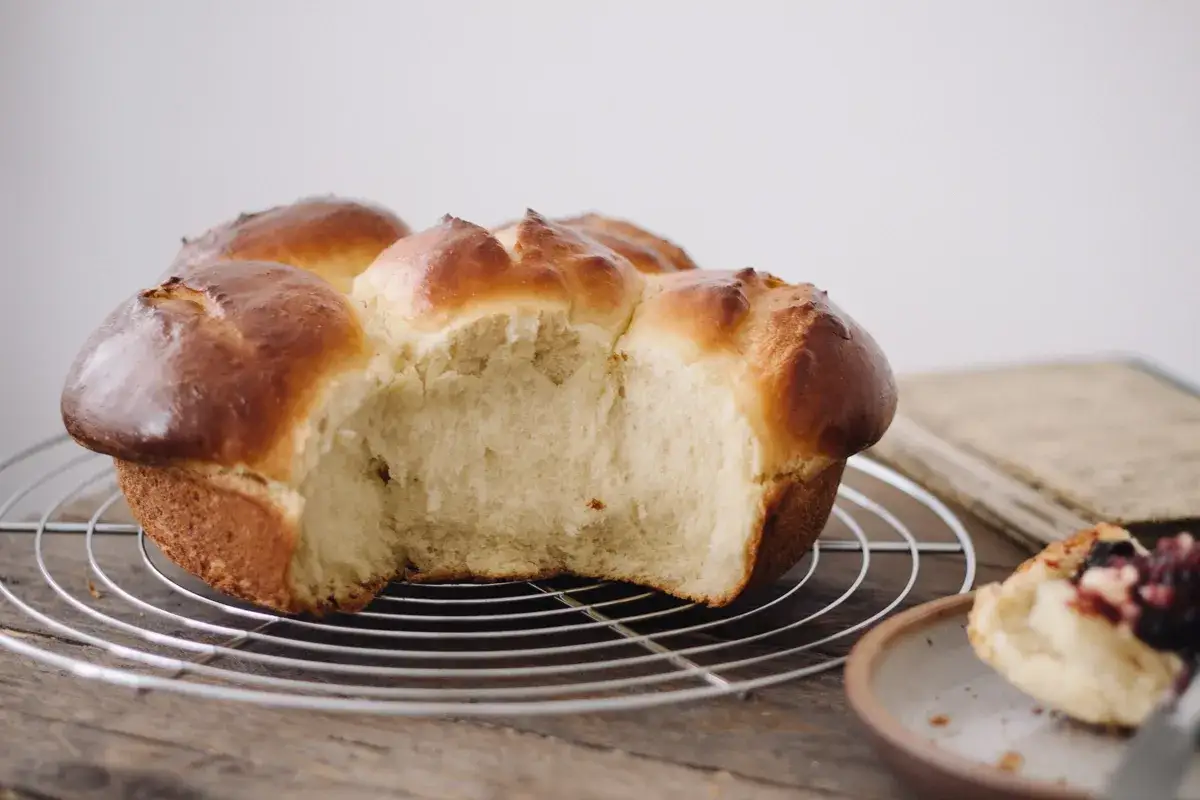 Une brioche dorée et moelleuse, parfaite pour une recette de brioche facile à la main. Une part est déjà dégustée.