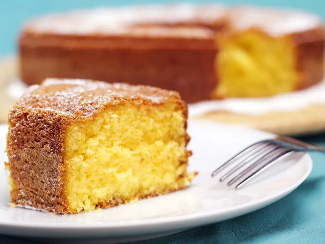 Tranche de gâteau au fromage blanc, saupoudrée de sucre glace, prête à être dégustée. Un délice inspiré par Cyril Lignac.