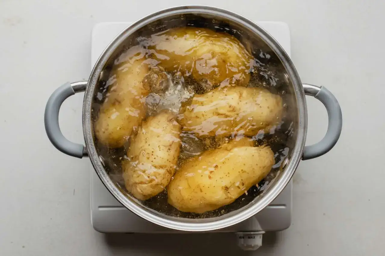 Cuisson pommes de terre à l'eau dans une casserole bouillante. Les tubercules dorés mijotent doucement, prêts à être dégustés.