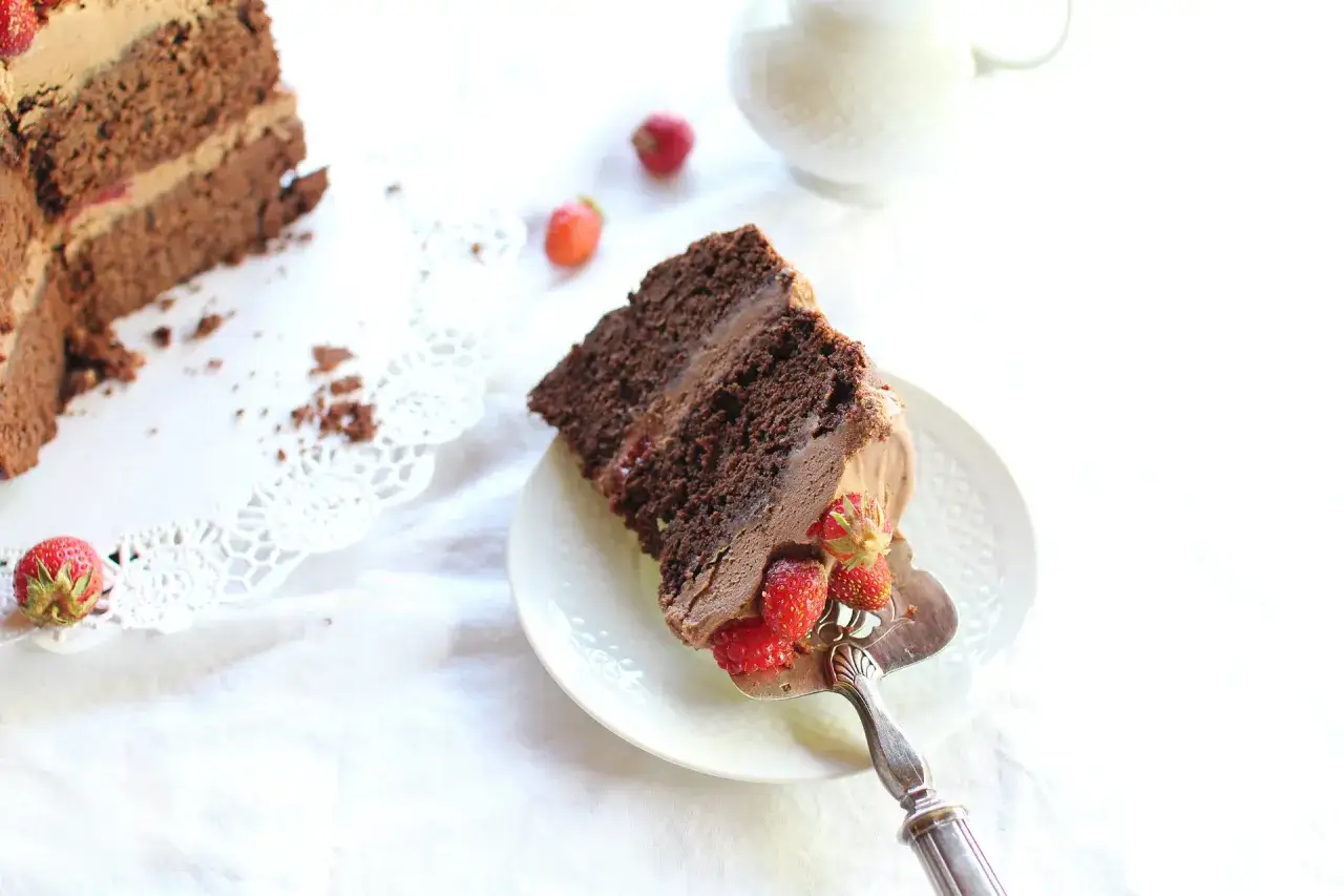 Un gâteau d'anniversaire facile et bluffant, une part de gâteau au chocolat garnie de fraises et framboises, prête à être dégustée.