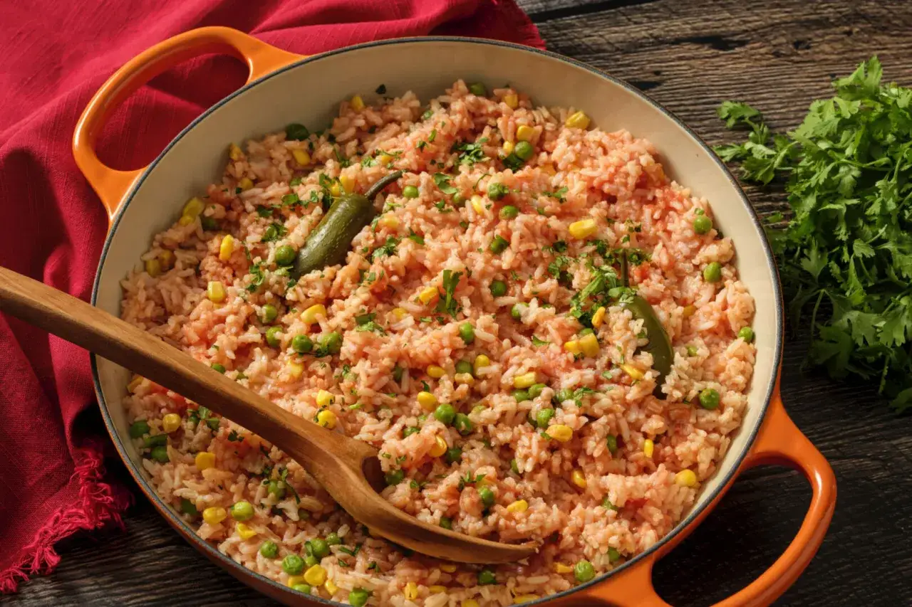 Riz rouge savoureux en cuisson, garni de petits pois, maïs et piments jalapeños, prêt à être servi.