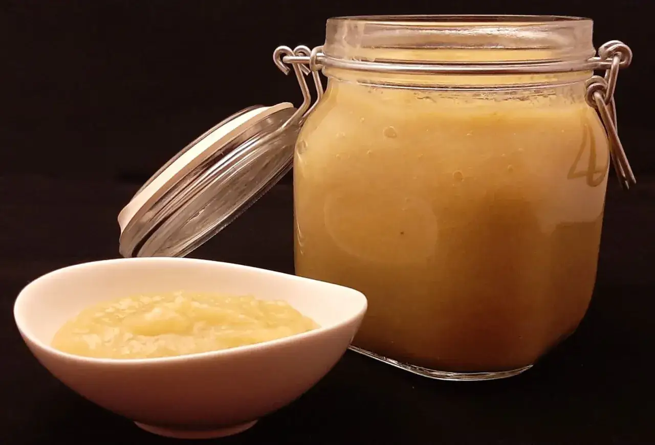 Un bocal ouvert et un bol de compote de rhubarbe maison, prête à être dégustée.