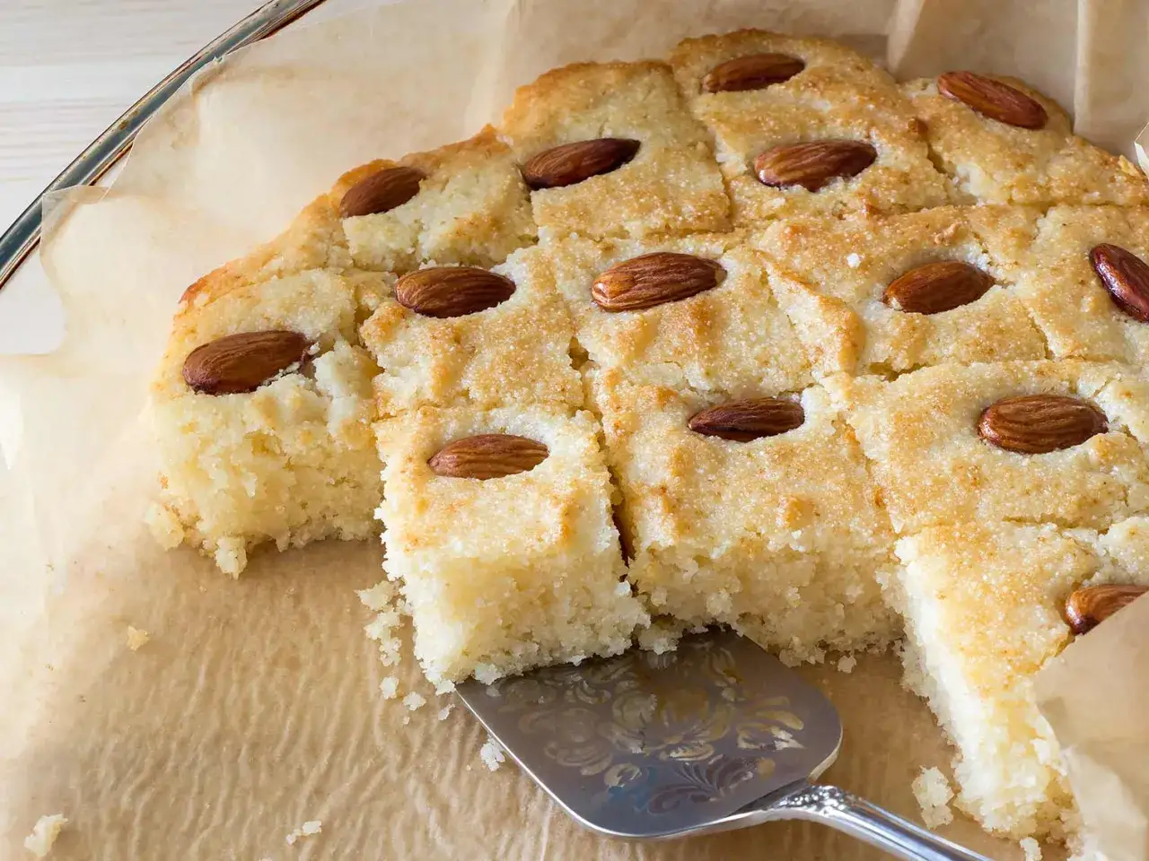 Un délicieux gâteau noix de coco, coupé en carrés et garni d'amandes entières, est prêt à être servi.