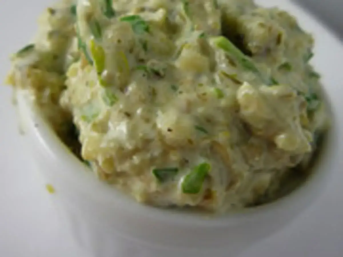 Sauce ravigote cr&eacute;meuse avec des herbes vertes fra&icirc;ches, servie dans un petit ramequin blanc.