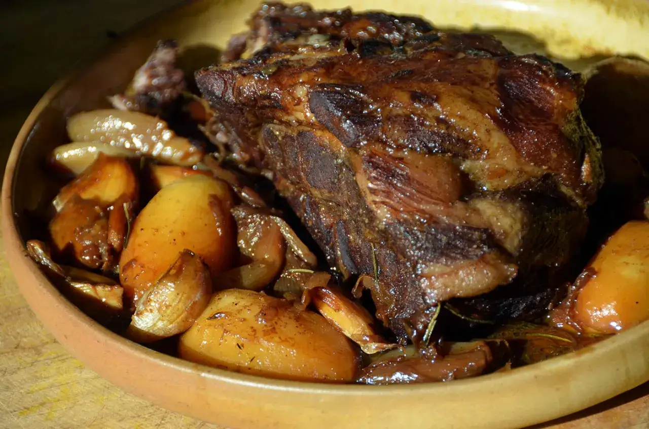 Un plat de viande cuisson lente, tendre et juteuse, mijotée avec des pommes de terre et de l'ail dans un plat en terre cuite.