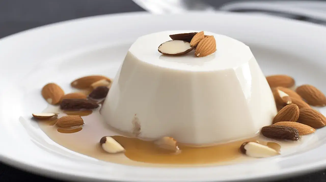 Un blanc-manger crémeux, orné d'amandes croquantes et d'un coulis ambré. La vraie recette du blanc-manger, un délice simple et raffiné.