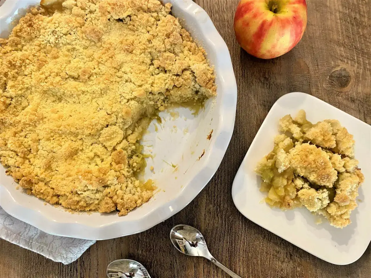 Un délicieux crumble pomme rhubarbe tout juste sorti du four, avec une portion servie sur une assiette.