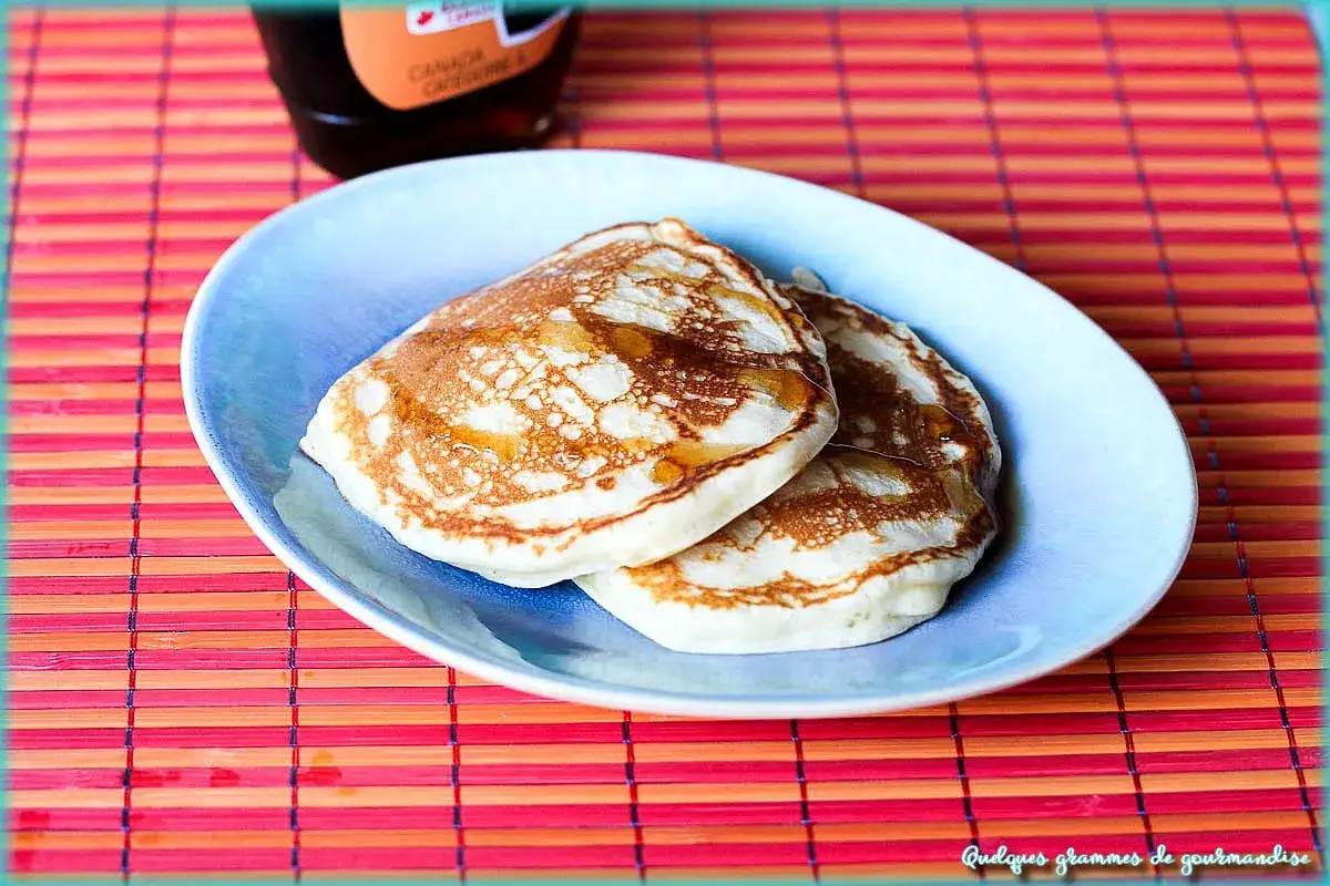 Deux pancakes dorés, nappés de sirop, prêts à être dégustés. Une recette simple pour des pancakes Cyril Lignac réussis.