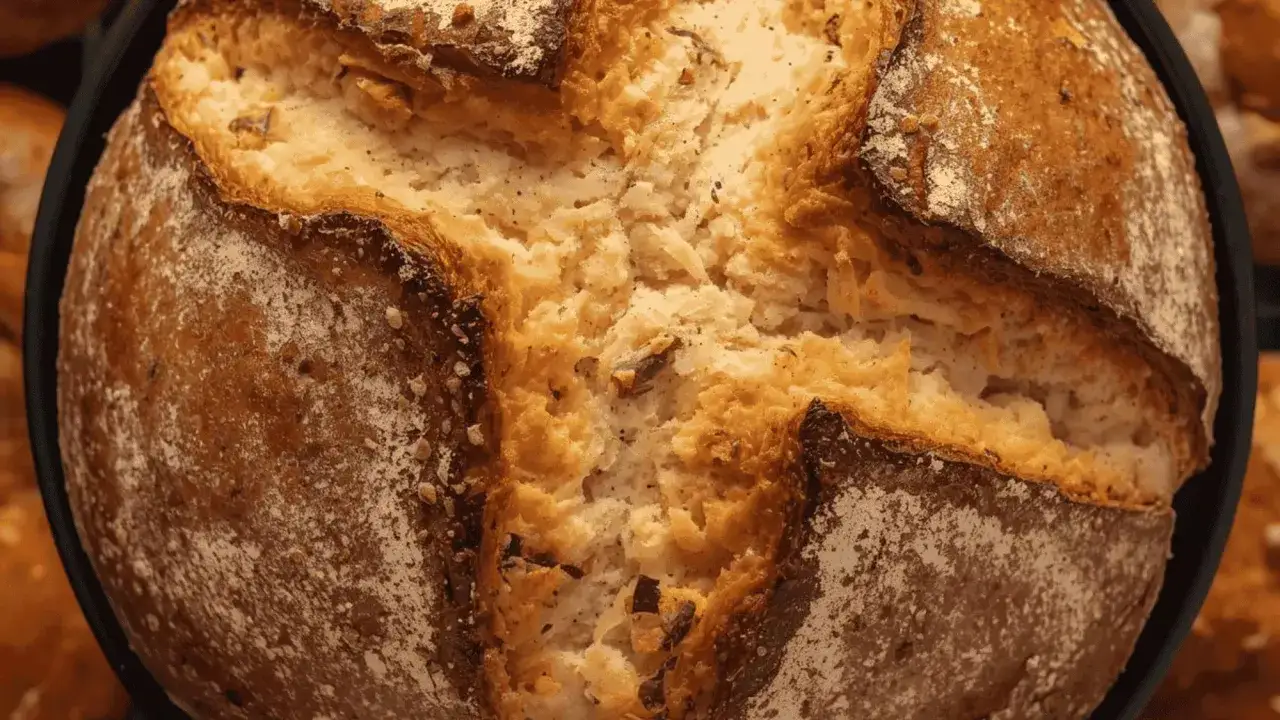 Gros plan sur un pain en cocotte, sa cro&ucirc;te dor&eacute;e et craquel&eacute;e r&eacute;v&egrave;le une mie a&eacute;r&eacute;e et savoureuse.