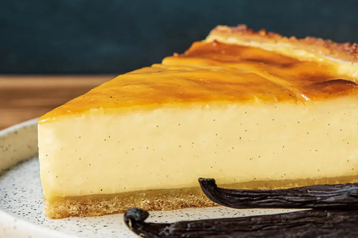 Tranche de flan onctueux à la vanille, parfait pour une recette flan sans pâte. La texture crémeuse et les grains de vanille sont visibles.
