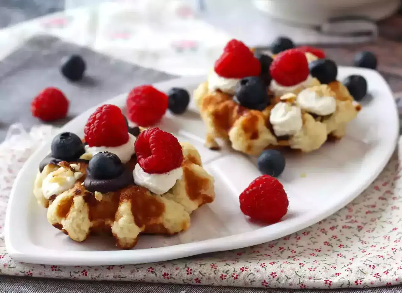 Délicieuses gaufres moelleuses garnies de crème, framboises et myrtilles. Une recette parfaite pour le petit-déjeuner ou le goûter.