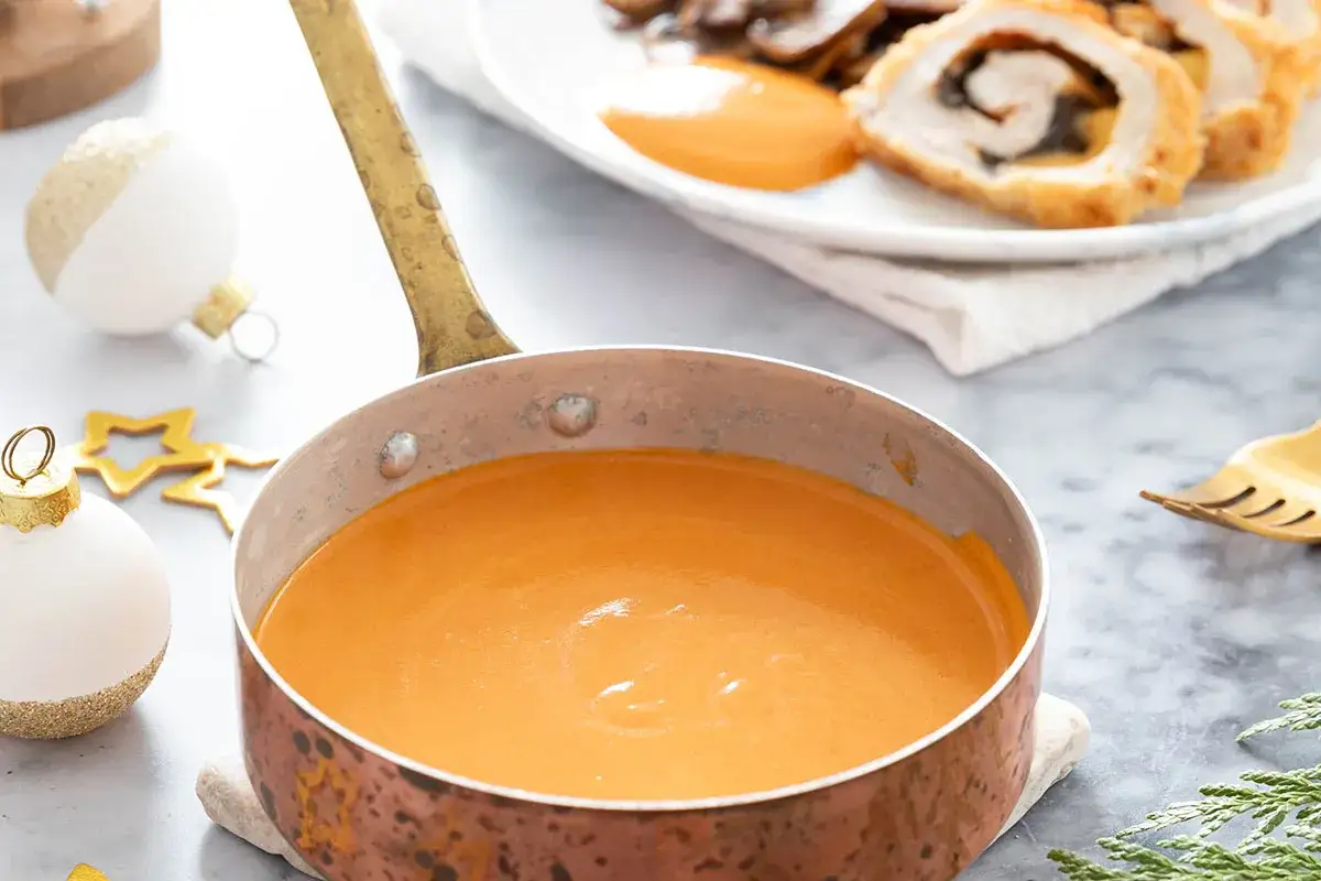 Sauce du chef onctueuse dans une casserole en cuivre, prête à accompagner un plat festif.
