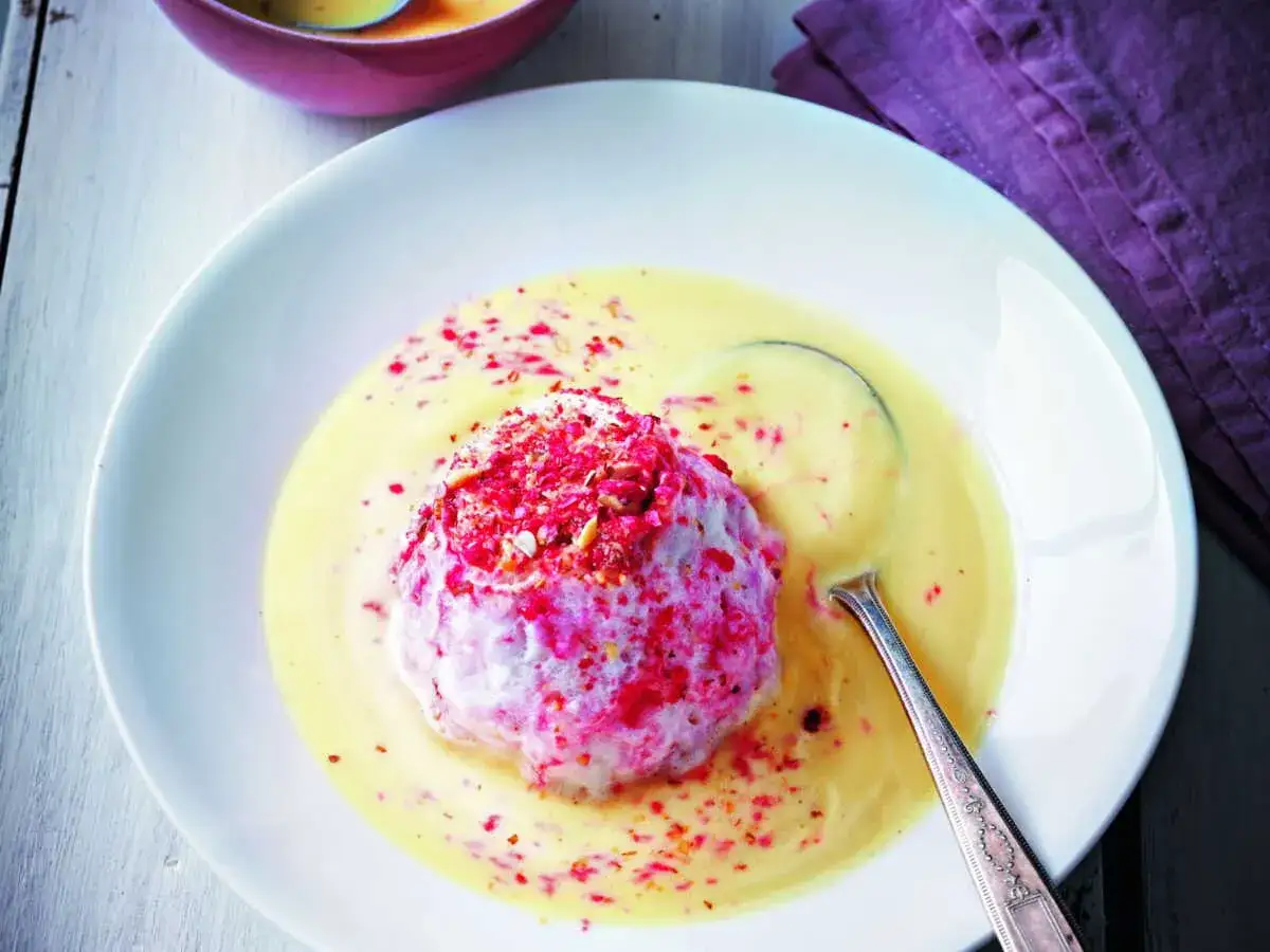 Un déliceux dessert de oeufs à la neige, une île flottante aérienne saupoudrée de fruits rouges, baignant dans une crème anglaise onctueuse.