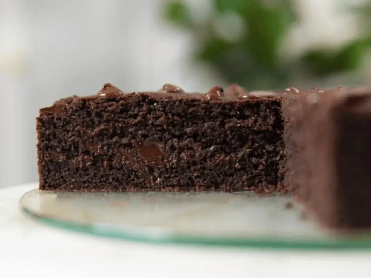 Gâteau yaourt chocolat moelleux, avec des pépites fondantes. Une tranche généreuse sur un plateau en verre.