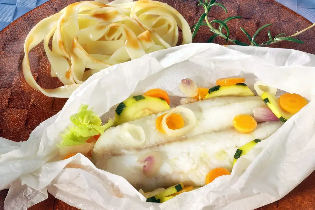 Délicieux cabillaud en papillote avec légumes croquants et pâtes fraîches. Un plat sain et savoureux.
