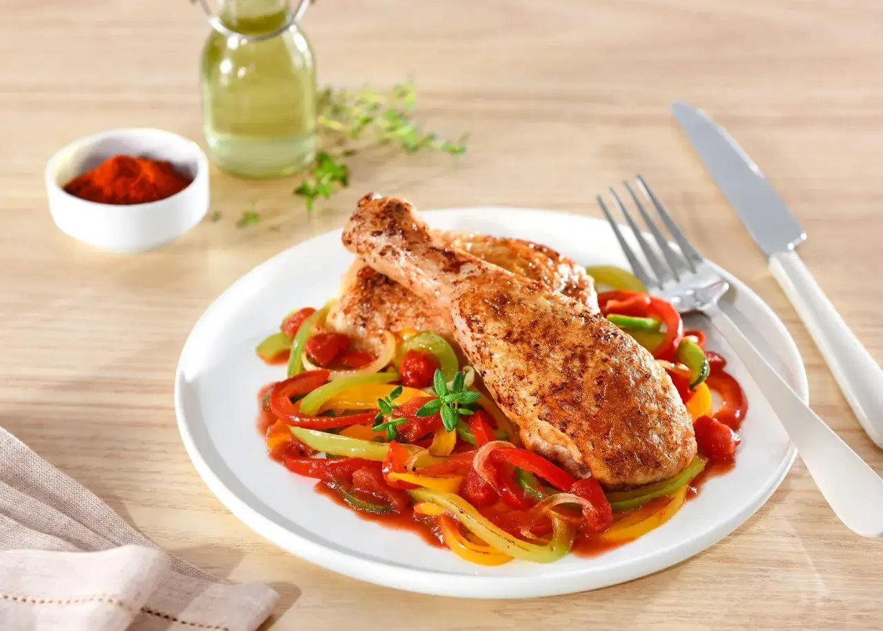 Poulet basquaise cookeo : deux morceaux de poulet r&ocirc;tis sur un lit de poivrons color&eacute;s et de tomates, garni de thym frais.