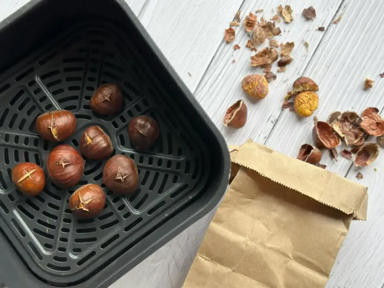 Châtaignes grillées dans un air fryer, prêtes à être dégustées. Les coquilles vides jonchent la table.