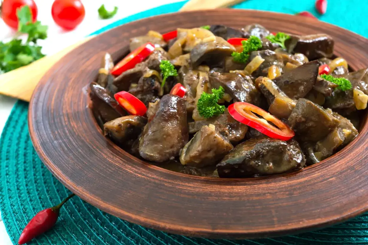Délicieux foie de volaille poêlé avec oignons, persil et piment rouge. Un plat savoureux prêt pour la cuisson.