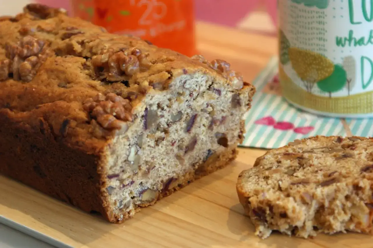 Un gâteau moelleux aux dattes et noix, avec une tranche coupée, prêt à être dégusté.
