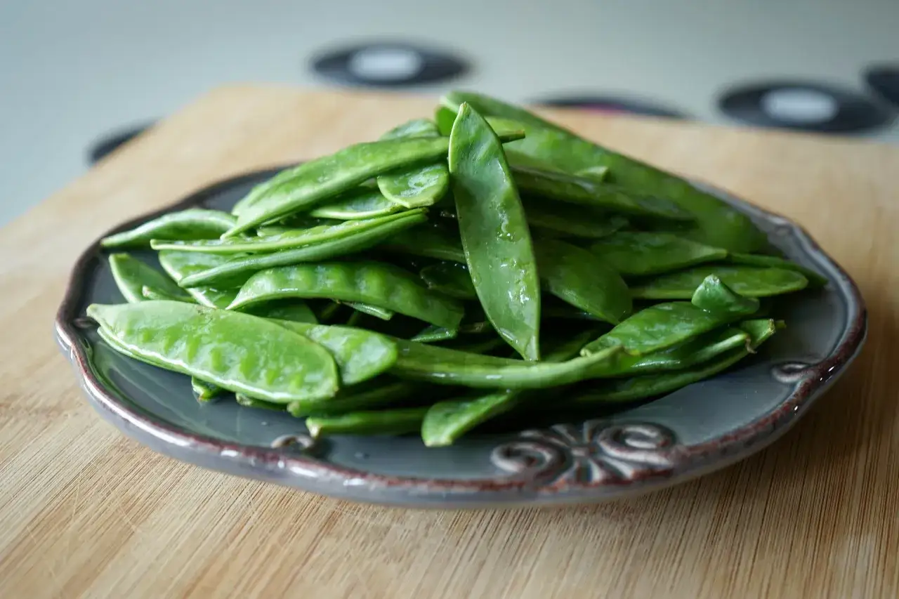 Une assiette de pois mange tout frais et brillants, pr&ecirc;ts &agrave; &ecirc;tre d&eacute;gust&eacute;s.