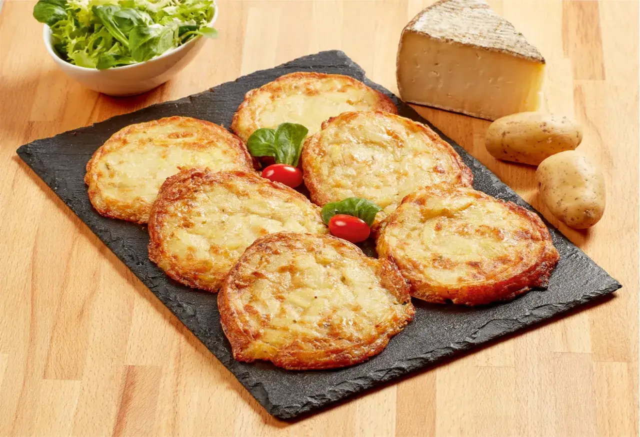 Six délicieuses truffades de l'Aubrac dorées, accompagnées de leurs ingrédients bruts : pommes de terre, fromage et salade verte.