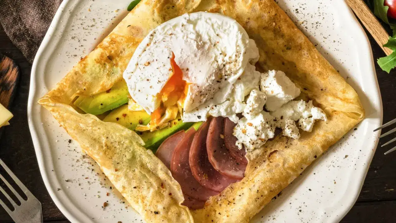 Crêpe salée garnie d'avocat, œuf poché coulant, jambon et fromage frais. Une idée parfaite pour une recette pâte à crêpe salée gourmande.