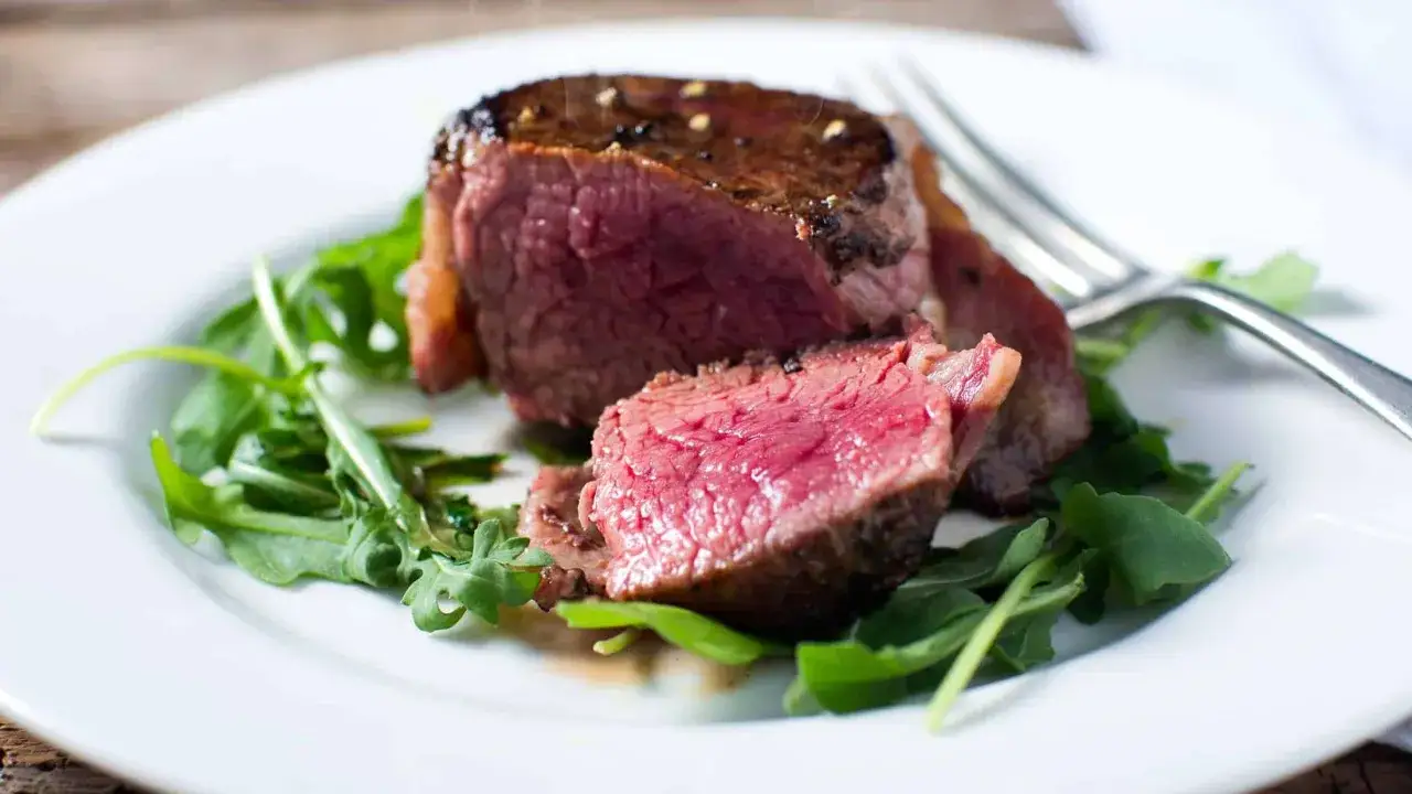 Un succulent filet de bœuf, cuisson parfaite, servi sur un lit de roquette fraîche.