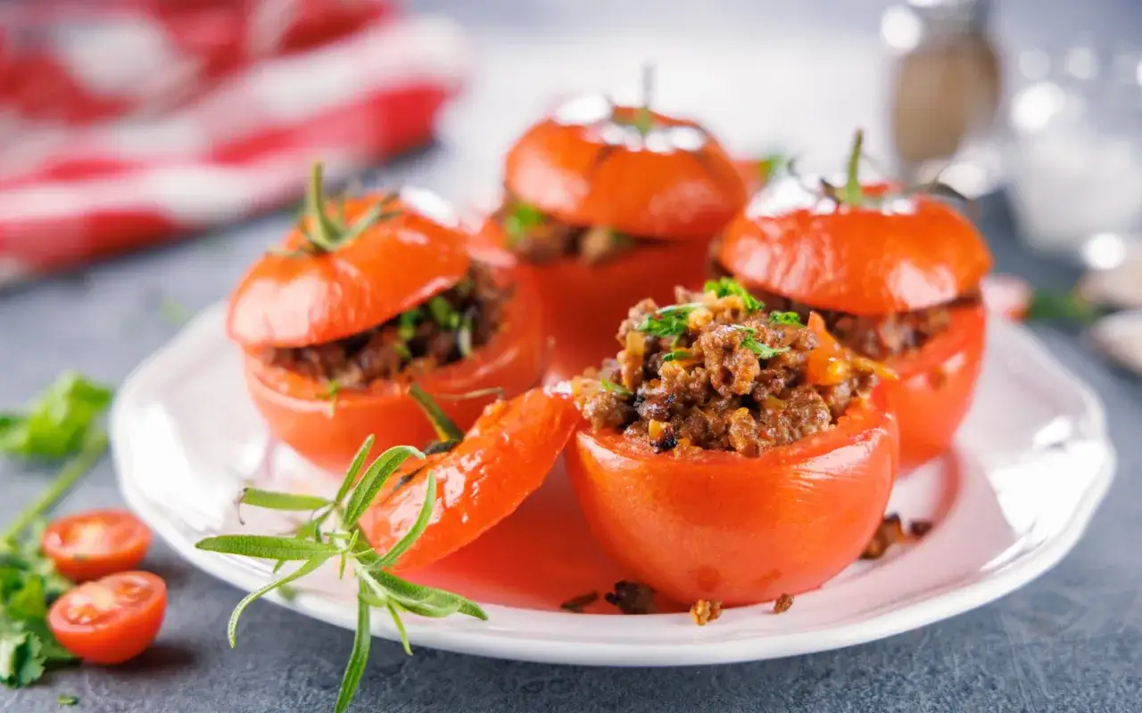 Tomates farcies app&eacute;tissantes sur une assiette blanche, garnies d'herbes fra&icirc;ches. Une recette simple et savoureuse.