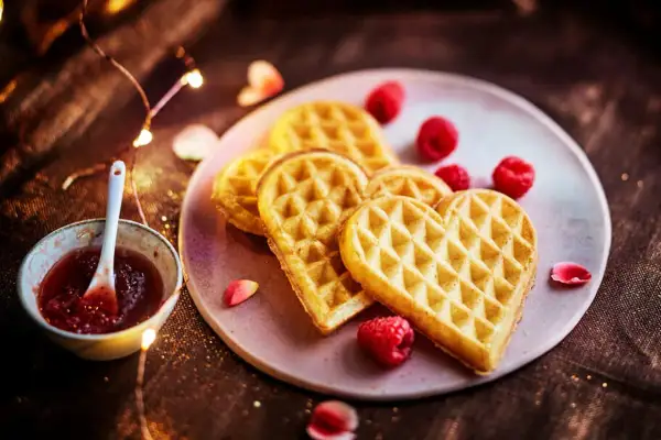 Gaufres en forme de cœur, parfaites pour une recette gaufre moelleuse, servies avec de la confiture de framboise et des fruits rouges.