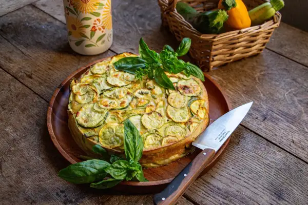 Un délicieux cake à la courgette, garni de basilic frais, prêt à être découpé.