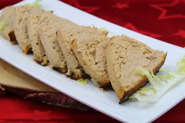 Tranches de pain de thon crème fraîche, garnies de salade, sur une assiette blanche.