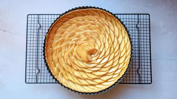 Tarte aux pommes recette de maman, magnifiquement décorée de fines tranches de pommes disposées en spirale sur une pâte dorée.