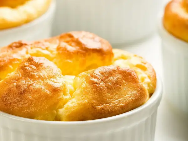 Soufflés au fromage dorés et gonflés dans leurs ramequins, prêts à être dégustés. Une recette simple pour un plat aérien.