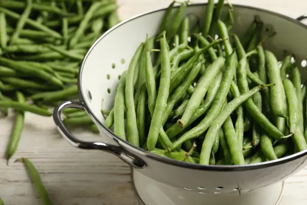 Haricots verts frais dans une passoire, prêts pour la cuisson. Une belle récolte verte pour un repas sain.
