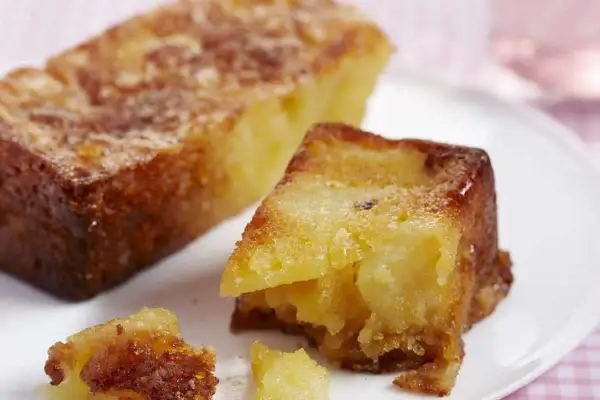 Un gâteau aux pommes moelleux et ultra rapide, doré et appétissant, servi sur une assiette blanche.