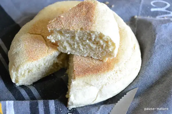 Un pain à la poêle, moelleux et doré, coupé en deux pour révéler sa mie aérée. Parfait pour le petit-déjeuner.