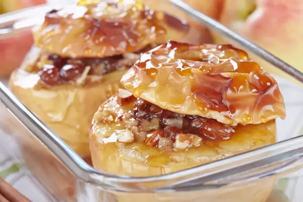 Deux pommes au four dorées, garnies de noix et de raisins secs, nappées d'un sirop brillant. Un délice gourmand.