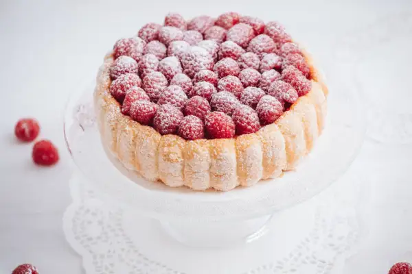 Charlotte aux framboises, un délice léger et fruité, ornée de fruits rouges frais et saupoudrée de sucre glace.