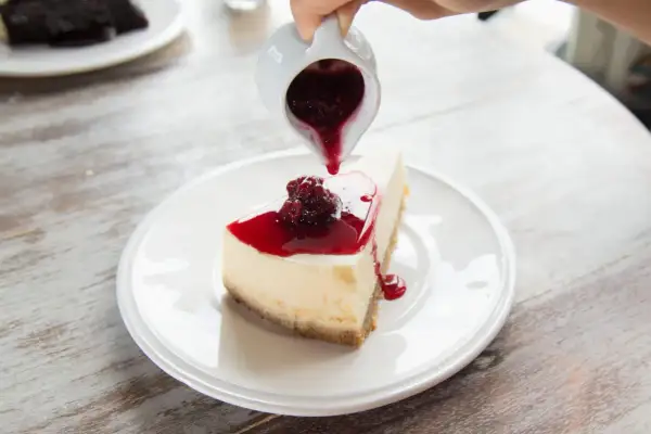 Un délicieux cheesecake garni de coulis de fruits rouges, un dessert rapide sans cuisson parfait pour se régaler.