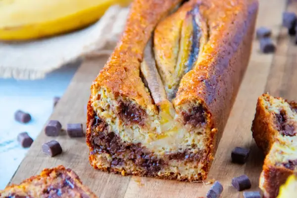 Un délicieux banana bread aux pépites de chocolat, garni de bananes entières sur le dessus.