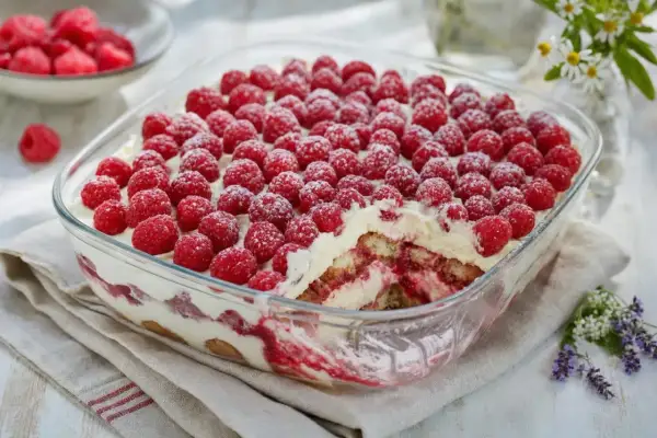 Un délicieux tiramisu framboise, généreusement garni de fruits rouges frais et saupoudré de sucre glace.