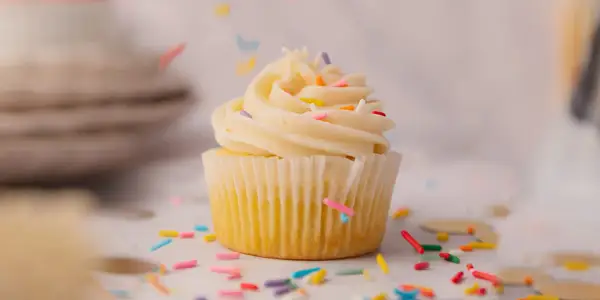 Un cupcake vanille avec glaçage crémeux et vermicelles colorés, parfait pour une recette de cupcake facile et festive.