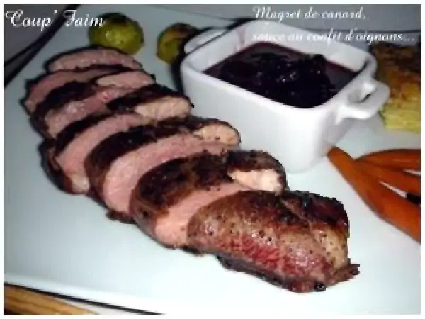 Magret de canard tranché, servi avec une sauce au confit d'oignons. Un délice pour les gourmands.