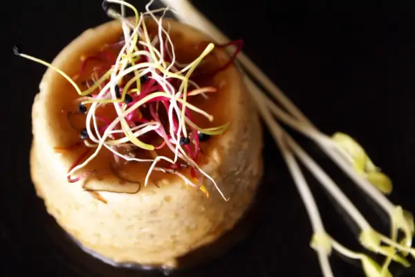 Un délicat flan de cuisson foie de volaille, garni de pousses colorées et de tiges de germes.