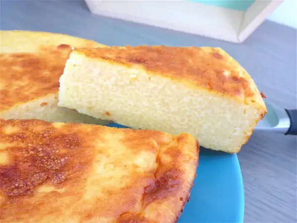 Un gâteau arabe semoule extra fine, doré et moelleux, servi sur une assiette bleue. Sa texture légère promet un délice.