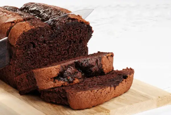 Un délicieux gâteau au chocolat sans beurre, coupé en tranches sur une planche en bois. Sa texture moelleuse et son goût intense invitent à la gourmandise.